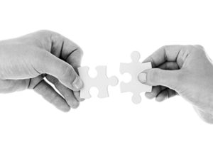 two hands putting together puzzle pieces